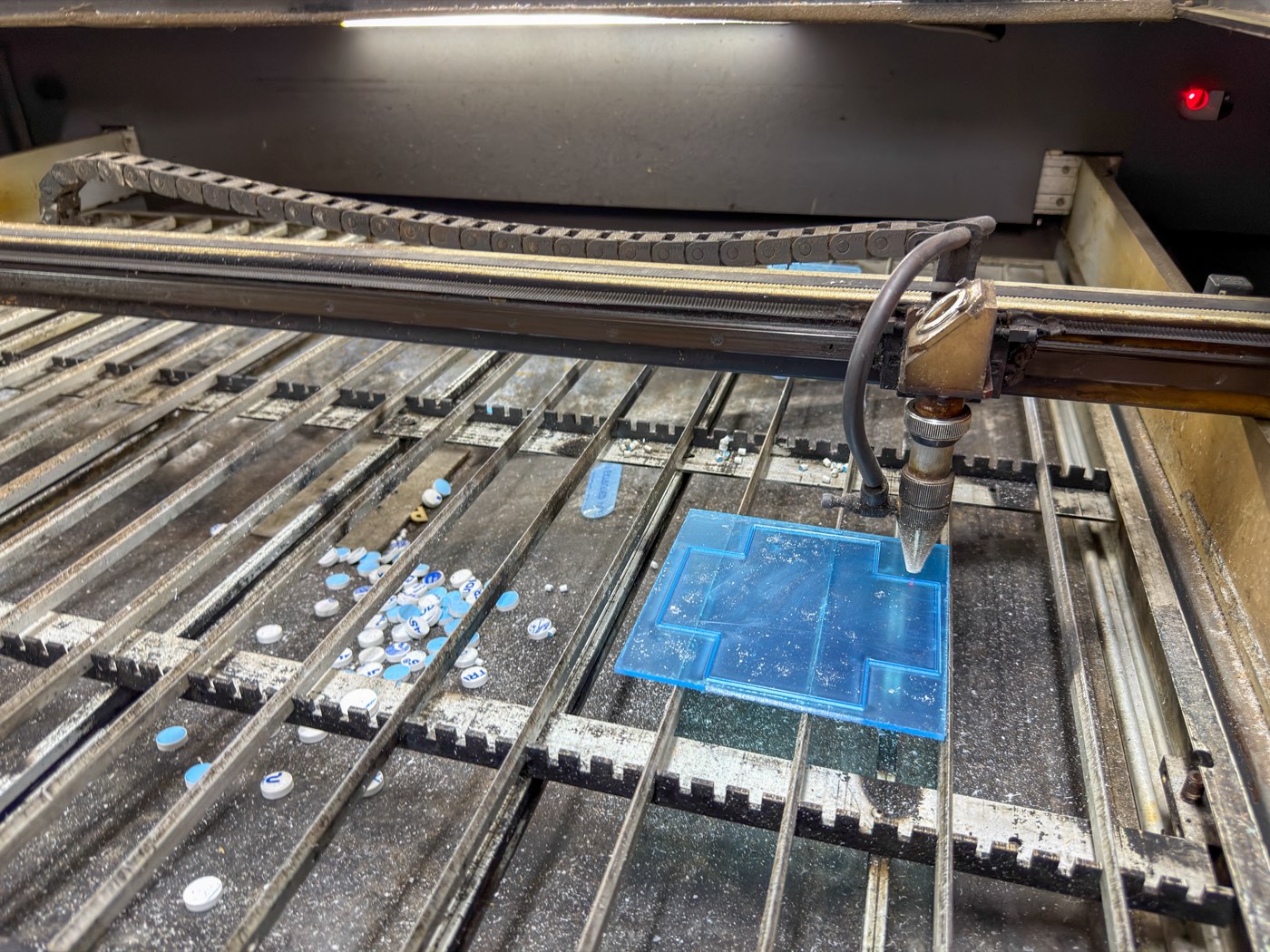 Laser head cutting a sheet of blue acrylic