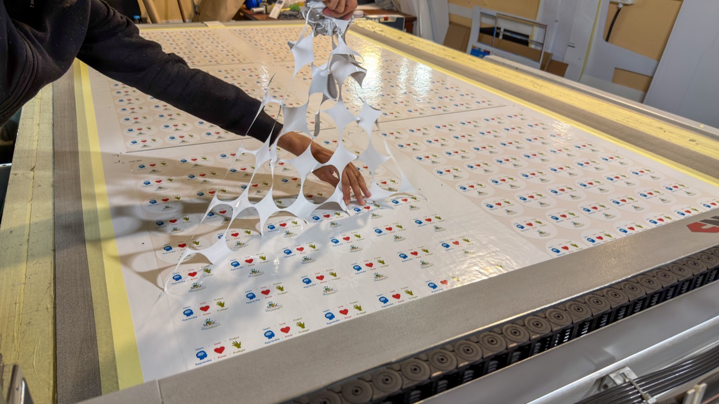 Hands removing waste from cut sheets