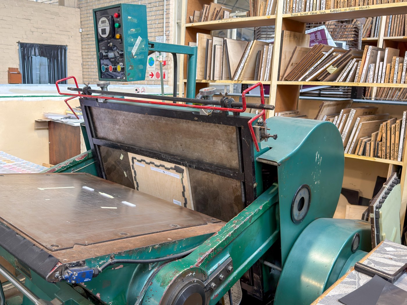 Platen die-cutter beside shelves of cutting dies